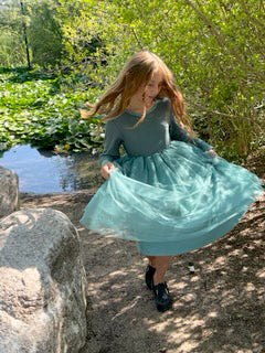 Girl in Ella Tulle dress standing by a pond with greenery in the background