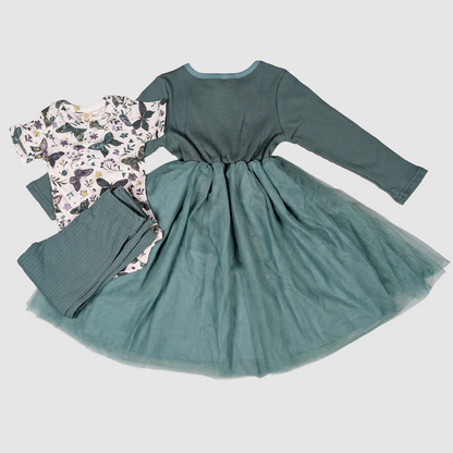 Green dress with long sleeves and floral patterned pants on a light gray background