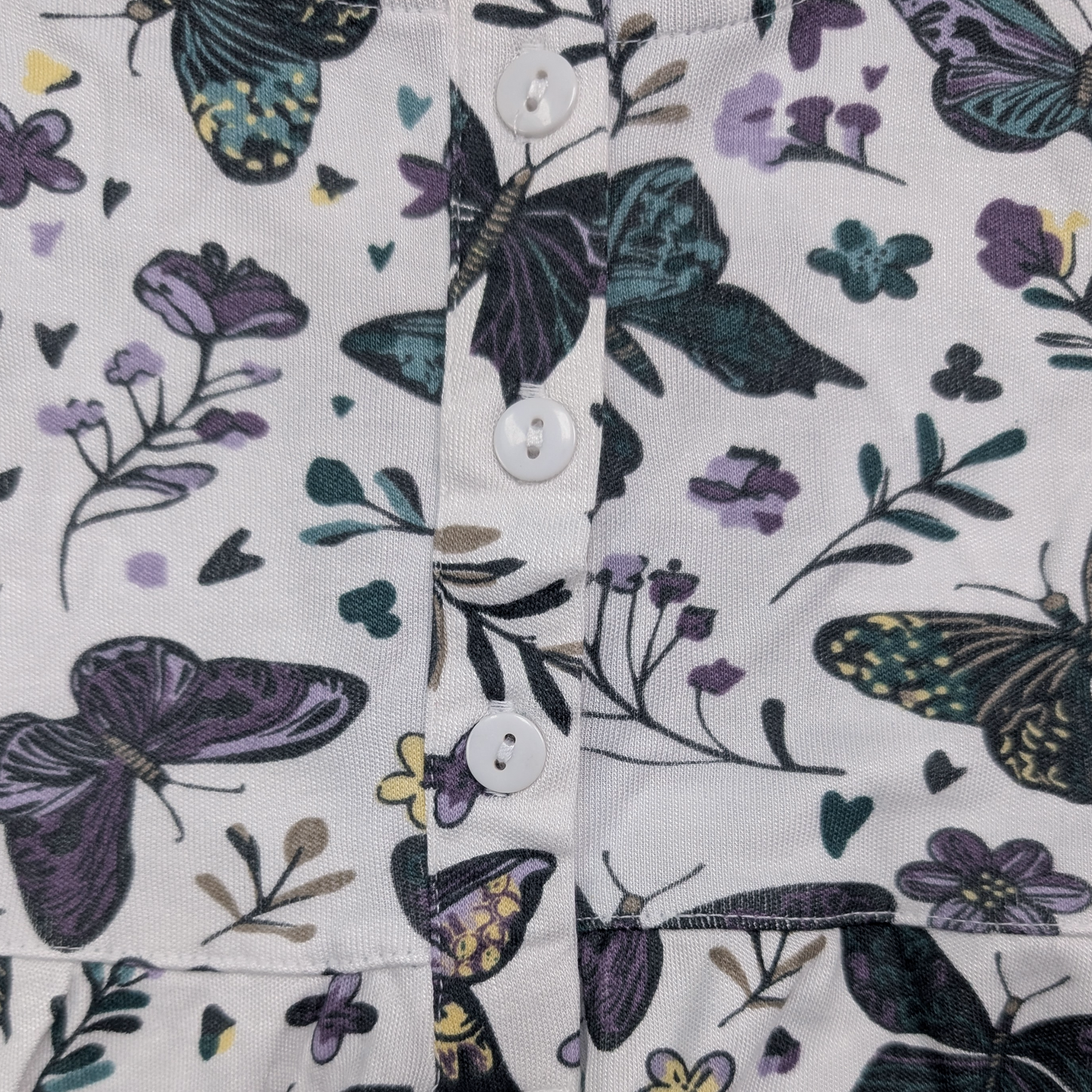 Close-up of button henley with dark butterfly and floral pattern on a white background