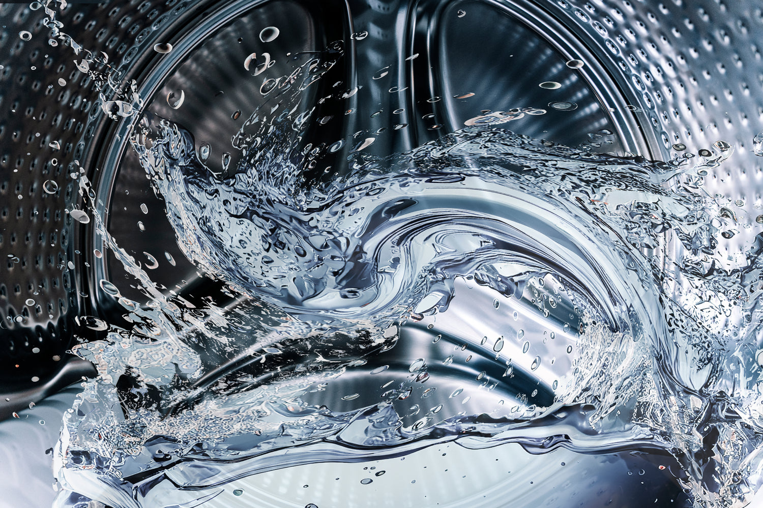 Close-up of a washing machine drum with water splashing inside